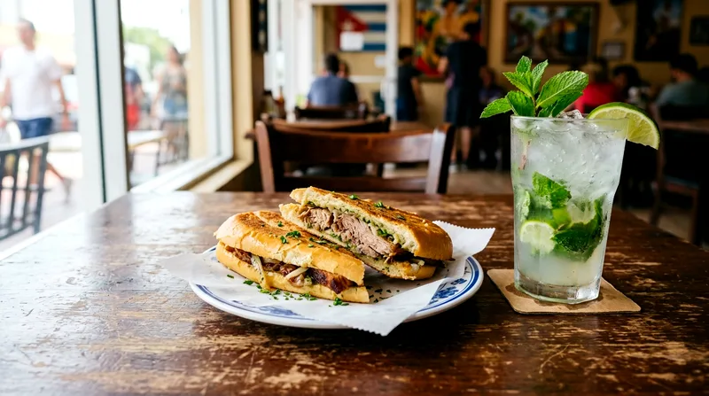 Pork sandwich and mojito on table at casual Little Havana restaurant in afternoon light.